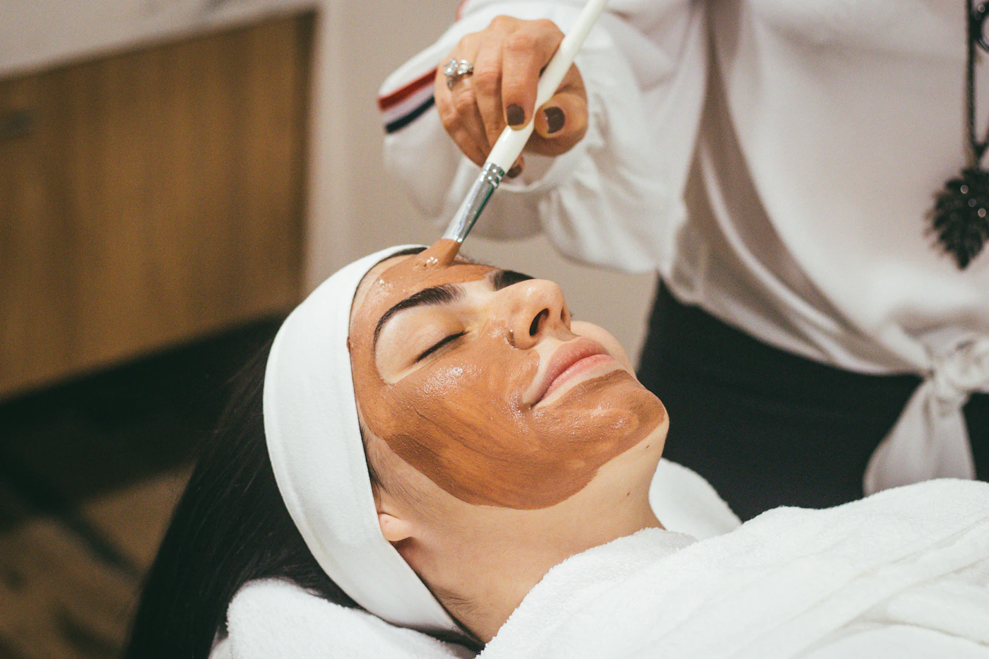 Profissional realiza um cuidado facial em uma sala de atendimento estético